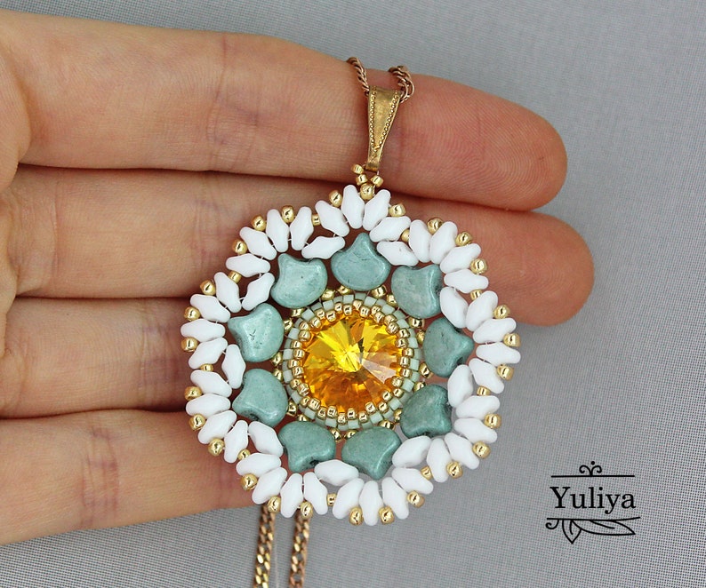 May include: A white and green beaded pendant necklace with a yellow crystal in the center. The pendant is in the shape of a flower.