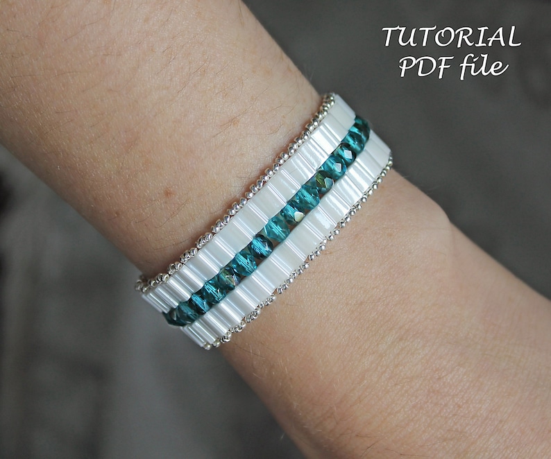 May include: A white and teal beaded bracelet with silver accents.  The bracelet is on a person's wrist.  The image includes the text "TUTORIAL PDF file".