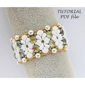 May include: A white beaded bracelet with gold and green accents. The bracelet is made with small white beads, gold beads, and green iridescent beads. The bracelet is on a grey background.