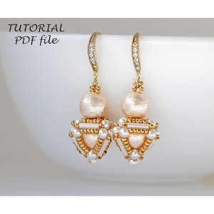 Könnte beinhalten: Ein Paar goldene Ohrringe mit einem Design aus weißen Perlen und goldenen Perlen. Die Ohrringe sind aus kleinen goldenen Perlen und weißen Perlen gefertigt.