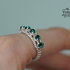 May include: A silver ring with a row of emerald green rhinestones.