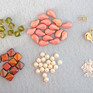May include: Assortment of beads in various colors and shapes, including pink teardrop beads, green faceted beads, brown square beads, white round beads, and gold metal beads.