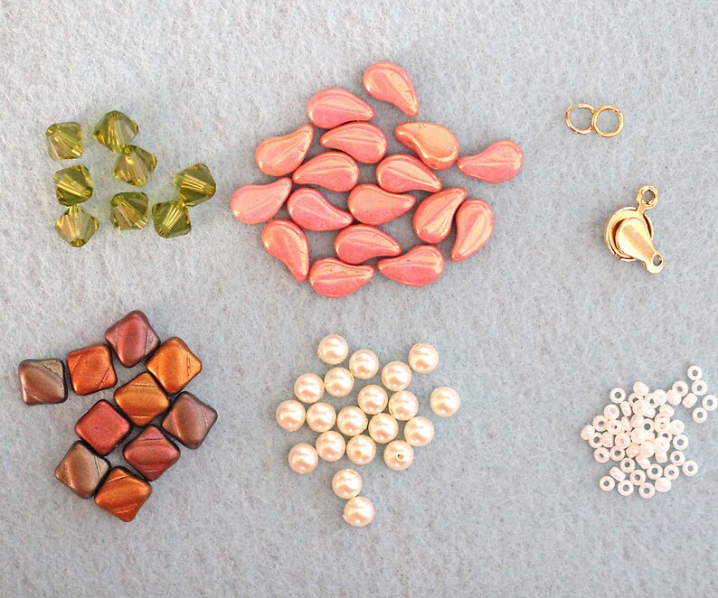 May include: Assortment of beads in various colors and shapes, including pink teardrop beads, green faceted beads, brown square beads, white round beads, and gold metal beads.
