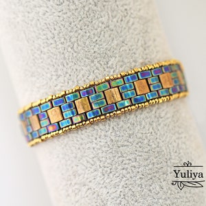 May include: A gold and iridescent blue beaded bracelet with a geometric pattern. The bracelet is made with small square beads.