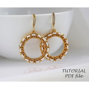 Può includere: Un paio di orecchini a cerchio dorati e bianchi con un design semplice. Gli orecchini sono appesi a una superficie bianca. TUTORIAL PDF file.