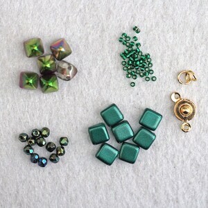 May include: Assortment of green and iridescent glass beads, including round, square, and teardrop shapes. Also included are gold-toned metal clasps and jump rings.
