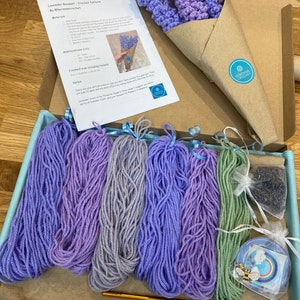May include: A crochet kit for making a lavender bouquet. The kit includes yarn in shades of purple and green, a crochet hook, a wooden dowel, and a small bag of dried lavender. The kit also includes a printed pattern with instructions for making the bouquet.