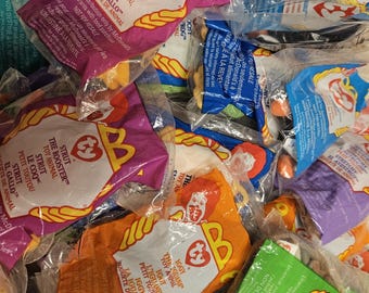 May include: A collection of Ty Beanie Babies in their original packaging. The bags are mostly red, yellow, blue, and green with the Ty logo and the name of the Beanie Baby printed on them. The Beanie Babies are all different colors and designs.