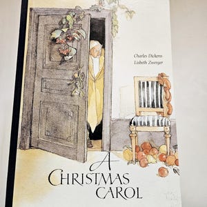 Può includere: Una copertina di libro vintage con un'illustrazione ad acquerello di un uomo che guarda da una porta. Il titolo del libro è "A Christmas Carol" di Charles Dickens e Lisbeth Zwerger.