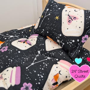 Puede incluir: Un juego de cama y almohada acolchada negra para mascotas con un diseño celestial. La tela presenta estrellas blancas, constelaciones y tarros con mariposas y flores en rosa, naranja y morado. El texto "24th Street Quilts" está en un corazón rosa.