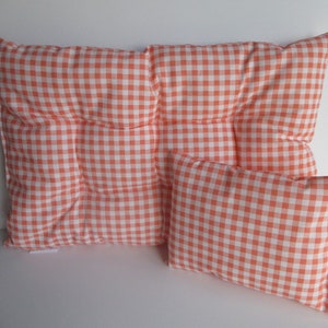 May include: Two orange and white gingham patterned pillows. The larger pillow is square and has a tufted design. The smaller pillow is rectangular.