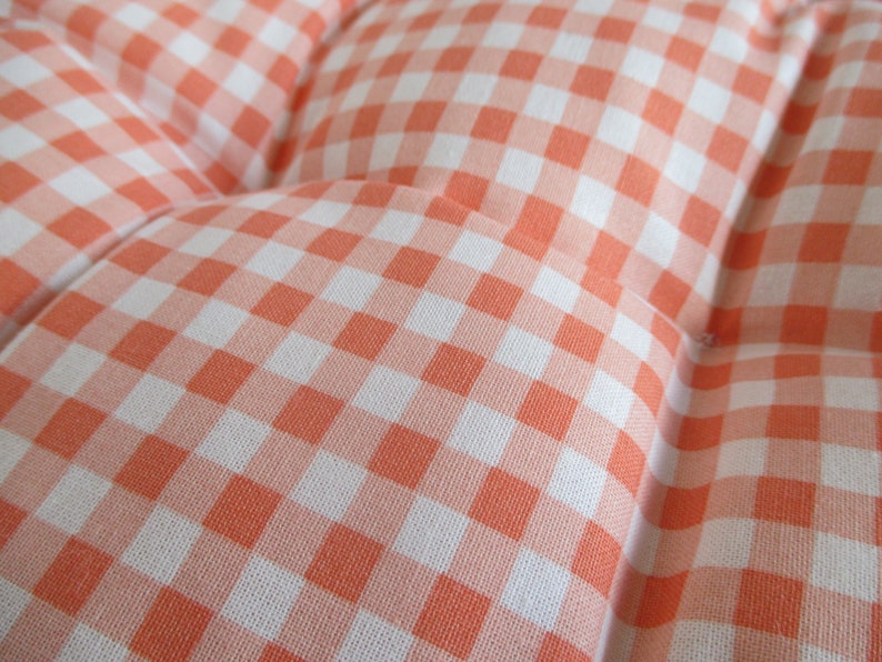 May include: Close-up of a pink and white gingham fabric. The fabric has a checkered pattern with small squares.