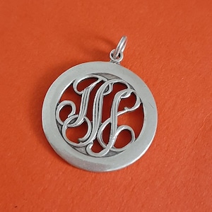Peut inclure: Pendentif en argent avec un design circulaire présentant un monogramme découpé des lettres "ME".