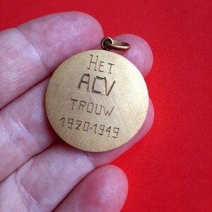 May include: A gold-colored round medal with the text "HET ACV TROUW 1920-1949" engraved on it.