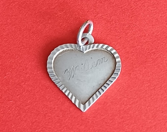 May include: A silver heart-shaped pendant featuring a textured, ribbed border and a smooth center engraved with the name Willem in cursive script. The pendant includes a small silver jump ring at the top for attachment to a chain or bracelet.