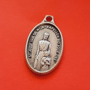 Peut inclure: Pendentif ovale en argent avec une image en relief d'un homme et d'un enfant. Le pendentif porte l'inscription "ST. JOZEF VAN DE WIJK - KAPELLEN BID VOOR ONS" sur le bord.