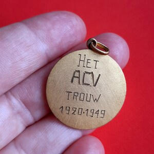 May include: A gold-colored round metal pendant with the inscription "HET ACV TROUW 1920-1949".