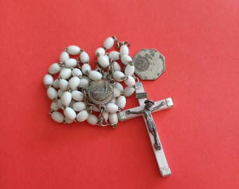 Terço católico antigo com contas brancas, cruz INRI de Jesus Cristo e medalha de Nossa Senhora de Lourdes no centro.