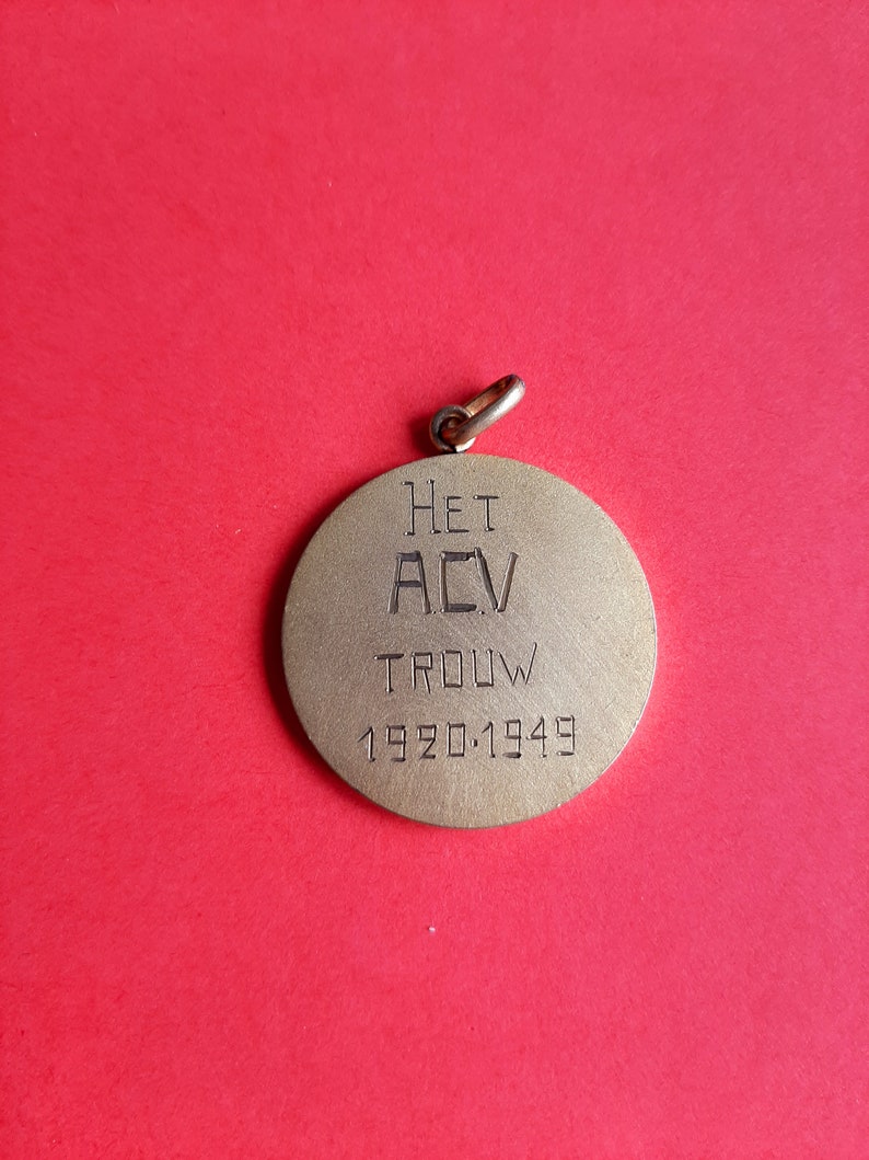 May include: A gold-colored metal medal with the text "HET ACV TROUW 1920-1949" engraved on the front.
