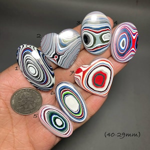 May include: Seven polished stones in various shapes, including ovals and hearts, with distinctive patterns. The stones display swirling designs in white, black, red, blue, and green. The size of the stones is between 2.9 cm and 4 cm.