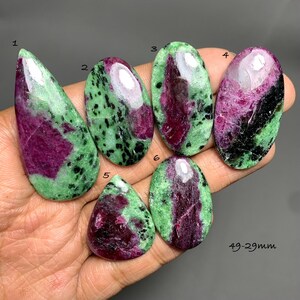 以下が含まれることがあります： 鮮やかなマゼンタ、深緑、黒の斑点模様を持つ、6つの研磨されたルビーインゾイサイトカボション。各石には1から6までの番号が付けられており、サイズは49mmから29mmの範囲です。石は滑らかで反射する表面を特徴としています。