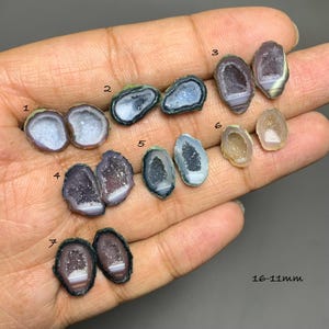 May include: A collection of small, polished agate geode slices labeled 1 through 7, featuring crystalline centers and banded edges in shades of purple, gray, blue, and white. The stones range in size from 16-11mm as indicated by the text.