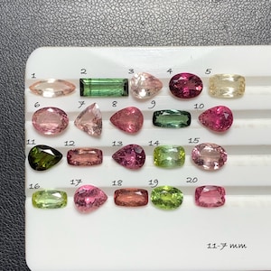 Könnte beinhalten: Eine Sammlung von zwanzig facettierten Edelsteinen auf einem weißen Display-Tablett, nummeriert von 1 bis 20. Die Steine haben verschiedene Formen wie oval, birnenförmig, rechteckig und marquise, in Rosa, Grün und Gelb. Text lautet 11-7 mm.