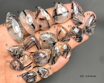 May include: A collection of eighteen polished rutilated quartz gemstones, each featuring distinct black needle-like inclusions within clear crystal. The stones are numbered 1 through 18, with sizes ranging from 32-16mm as indicated by the text.