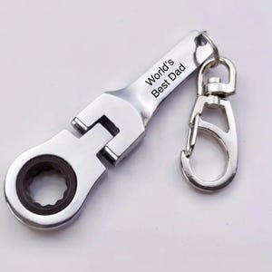 May include: A silver wrench keychain with a black inscription that reads "World's Best Dad" and a silver swivel clip.