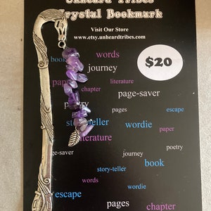 Könnte beinhalten: Ein silbernes Lesezeichen mit einem Pferdekopfdesign und einer Reihe von Amethystkristallen. Das Lesezeichen befindet sich auf einem schwarzen Hintergrund mit den Worten "Unheard Tribes Crystal Bookmark" und "20 €".