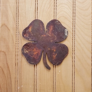 May include: A rusty metal four-leaf clover cutout against a light wood background.