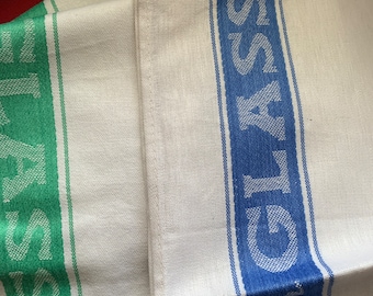 Puede incluir: Dos toallas de cocina blancas con rayas azules y verdes y las palabras "GLASS" y "TEA" impresas en ellas.