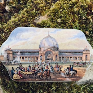 Puede incluir: Una caja de cerámica vintage con una imagen pintada de un gran edificio con una cúpula y personas delante. El edificio está pintado en tonos de marrón, blanco y gris. Las personas están pintadas en tonos de marrón, azul y rojo.