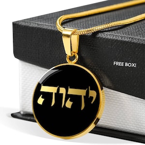 May include: Gold necklace with a black round pendant featuring the Hebrew word "Chai" in gold lettering. The necklace is displayed on a black box with the words "FREE BOX!" printed on it.
