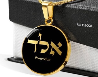 May include: Gold necklace with a round pendant featuring the Hebrew word for protection, "Amulet", in gold lettering on a black background. The pendant is on a gold chain.