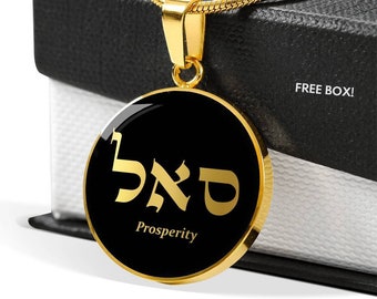 Puede incluir: Un collar de cadena dorada con un colgante redondo que presenta la palabra hebrea para la prosperidad, "ברד", en letras doradas sobre un fondo negro. El colgante está unido a una cadena dorada.