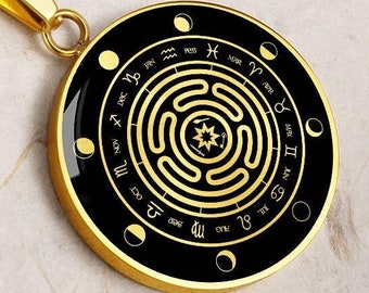 May include: Gold necklace with a round pendant featuring a black background and gold zodiac symbols and a circular maze design.
