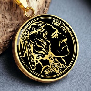 May include: Gold-coloured pendant necklace featuring a black and gold coin design. The coin depicts a profile with the word "LIBERTY" and the year "1930". The necklace has a gold chain and a gold-coloured pendant holder.