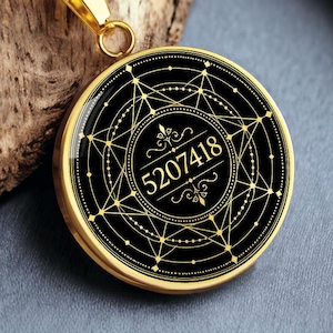 May include: Gold-toned pendant necklace with a black circular face. The face features a geometric design with the number "5207418" in the center. The necklace has a gold chain and a clasp.