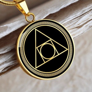 Peut inclure: Un collier en or avec un pendentif rond sur fond noir et un motif géométrique en or représentant un cercle, un carré et un triangle.