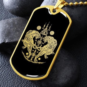 May include: Gold pendant necklace with a black enamel dog tag featuring a detailed image of two golden tigers facing each other. The tigers are surrounded by intricate designs and symbols.