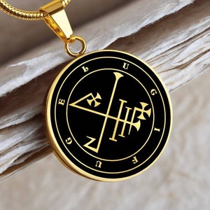 May include: A gold chain necklace with a black circular pendant featuring a gold sigil with the letters 'ELUGIGUF' around the edge.