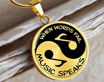May include: Gold necklace with a round pendant featuring a yin yang symbol with a musical note on each side. The pendant has the text "When words fail music speaks".