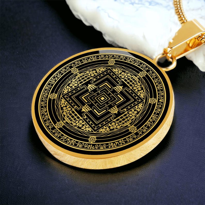 May include: Gold pendant necklace with a black circular charm featuring a detailed gold mandala design.