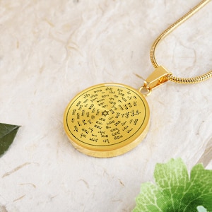 May include: A gold-toned necklace with a round pendant featuring a Star of David and Hebrew text. The pendant is inscribed with a circular pattern of Hebrew letters.