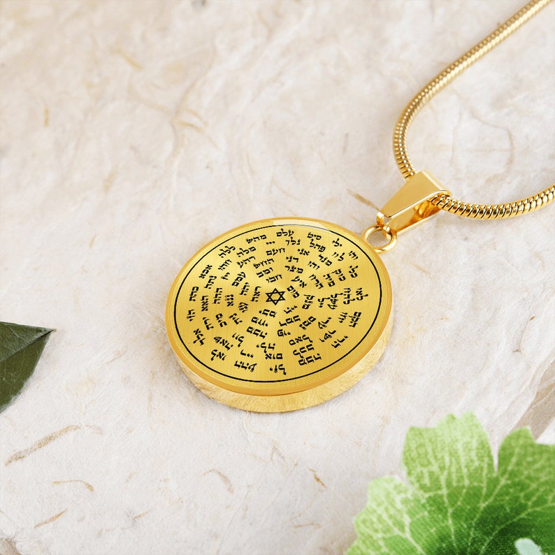 May include: A gold-toned necklace with a round pendant featuring a Star of David and Hebrew text. The pendant is inscribed with a circular pattern of Hebrew letters.