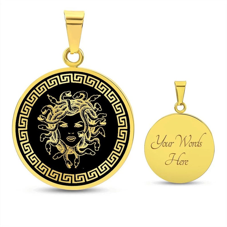 May include: Gold-tone pendant necklace featuring a black enamel circle with a gold Greek key border and a gold Medusa head design. The back of the pendant is plain gold with the text "Your Words Here".