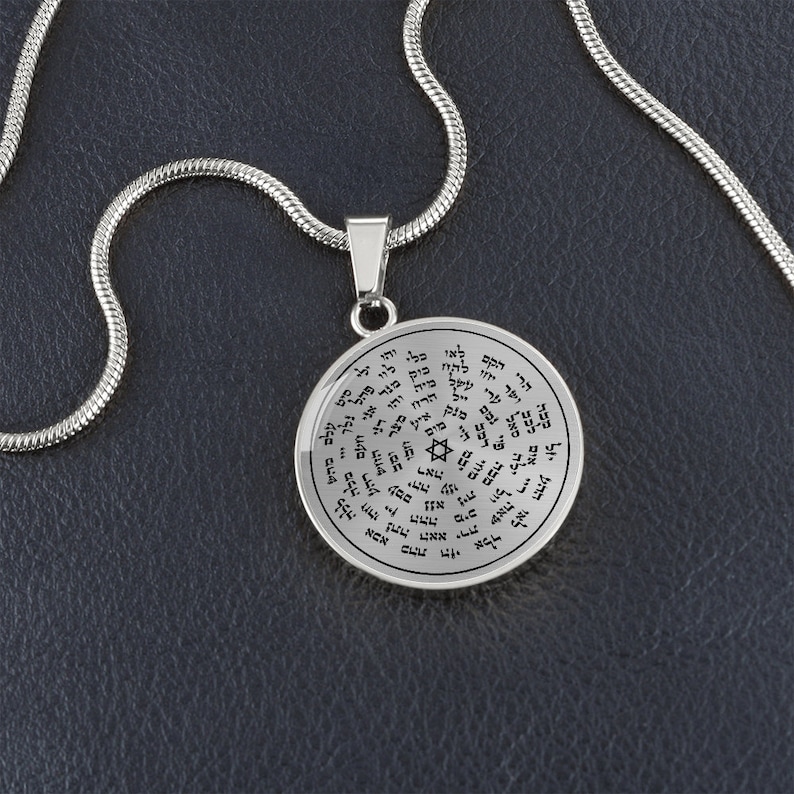 May include: A silver chain necklace with a round pendant featuring Hebrew text and a Star of David. The pendant is inscribed with a circle of Hebrew text.