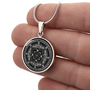 May include: A silver chain necklace with a black round pendant featuring a silver mandala design.