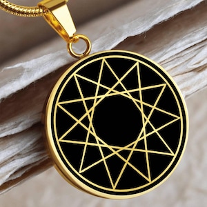 May include: A gold chain necklace with a pendant featuring a black circle with a gold eight-pointed star design.
